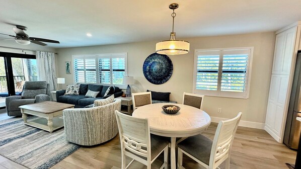 A spacious living room with a round dining table, a gray sofa, and a ceiling fan.