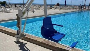 A poolside area with a blue chair and a pool lift. - E805 Great Gulf View, 3 pools, Gym & Tennis Court (Panama City)