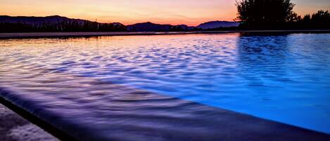 A serene pool at sunset with a clear view of distant mountains.