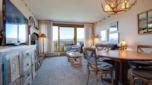 Une chambre d’hôtel dotée d’une grande fenêtre, d’un coin repas, d’une cheminée et d’un lustre.