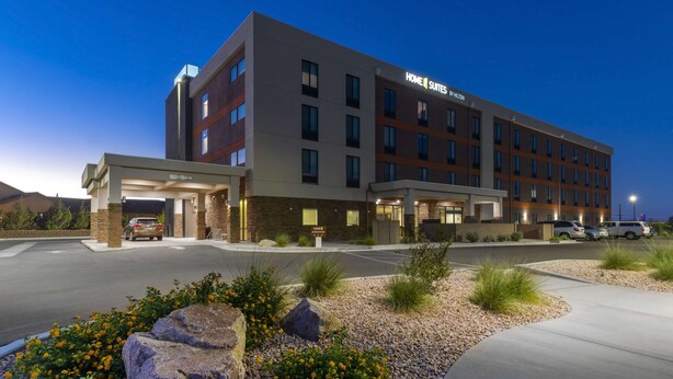 A multi-story hotel with a modern design, featuring a covered entrance and a parking lot.