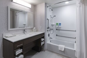 A modern bathroom with a large mirror, two sinks, a bathtub, and a shower. - Home2 Suites by Hilton Kingman (Kingman)