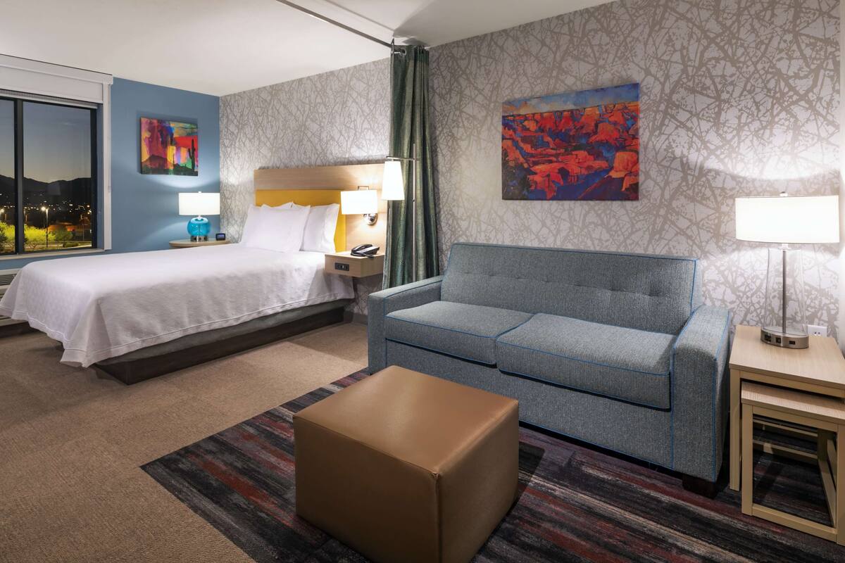 Ein Hotelzimmer mit Bett, Sofa, kleinem Tisch und Nachttisch.