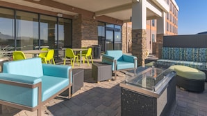 An outdoor patio with seating, including sofas and chairs, and a glass-top table.