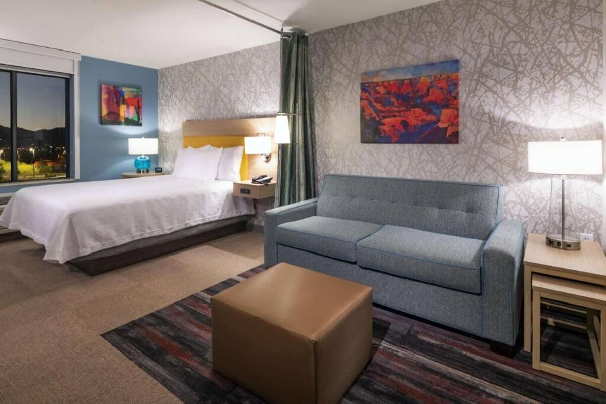 Ein Hotelzimmer mit Bett, Sofa, kleinem Tisch und Fenster mit Blick.