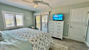 Ein Schlafzimmer mit Bett, Kommode, Fernseher und einer Tür.