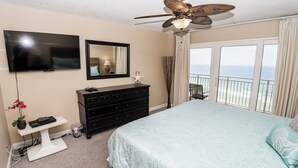 A bedroom with a bed, a dresser, a TV, and a balcony with a view of the ocean. - D1003 Private covered parking spot, Gulf Front! (Panama City Beach)