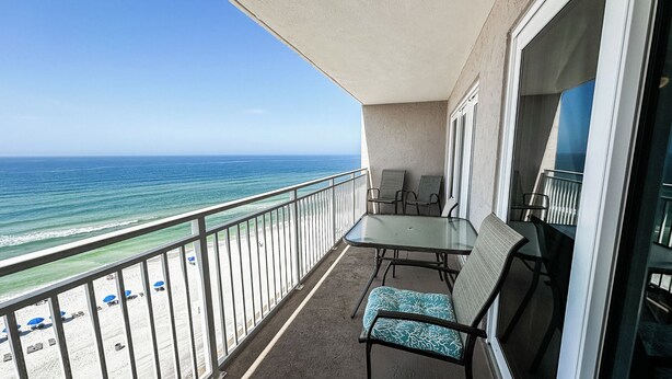 A balcony with a glass table and chairs, overlooking a beach and ocean. - D1003 Private covered parking spot, Gulf Front! (Panama City Beach)