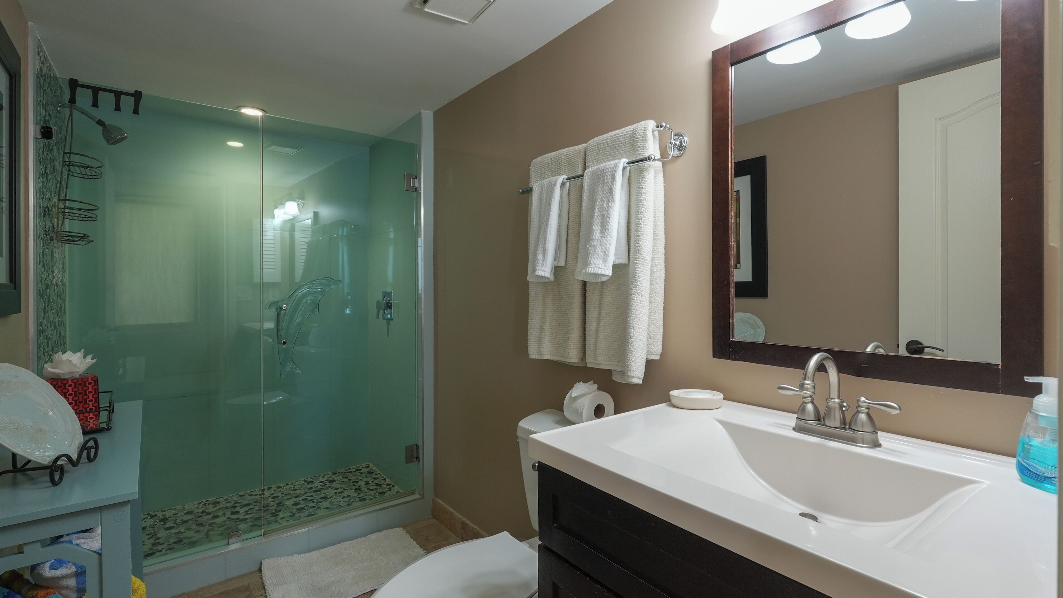 A bathroom with a glass-enclosed shower, a white sink, a mirror, and a towel rack.