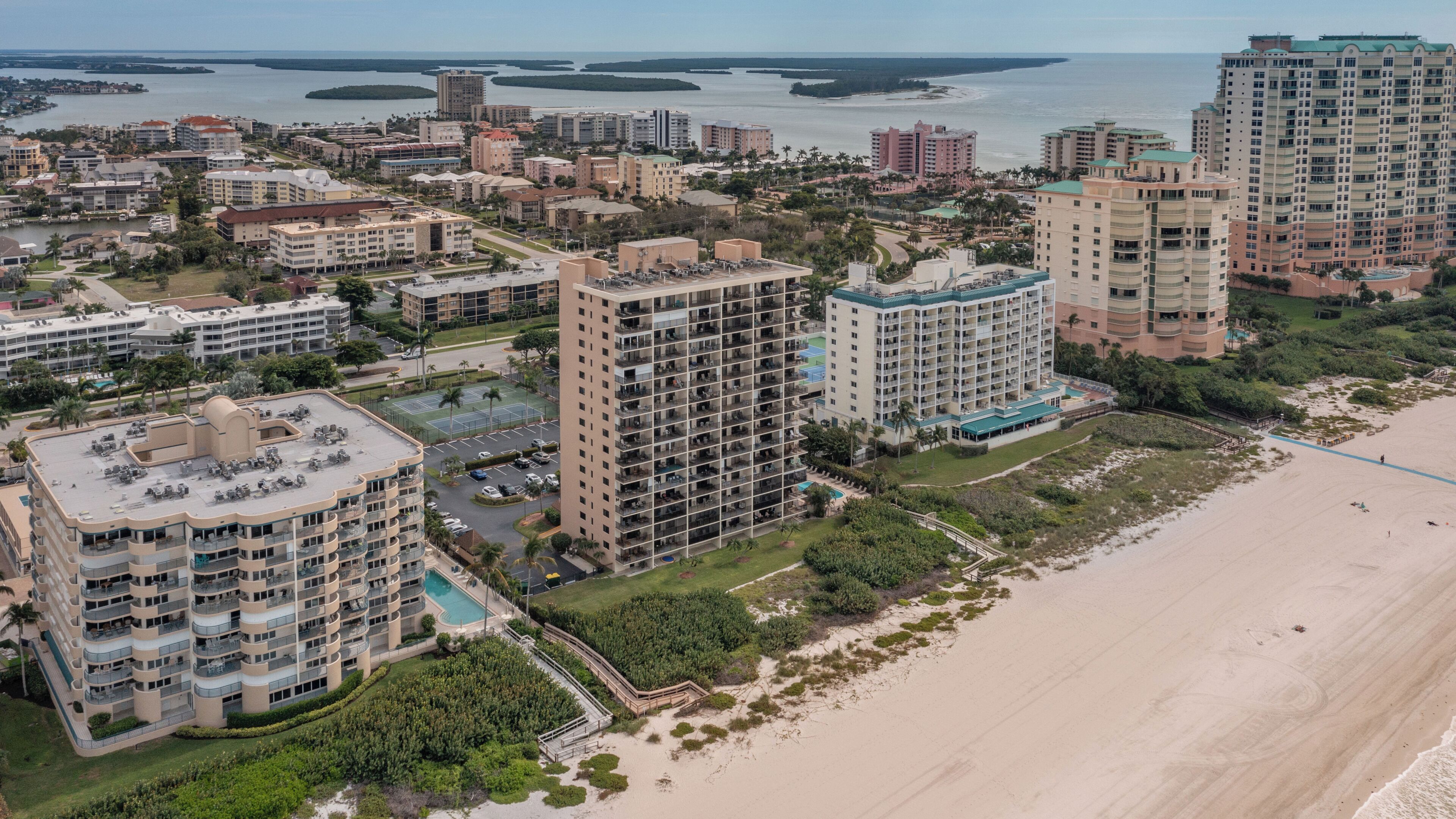 A coastal hotel complex with multiple high-rise buildings, a beach, and a marina.