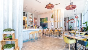 A modern restaurant with a bar area, wooden flooring, and multiple seating options including bar stools and tables.