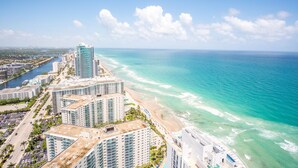 A coastal cityscape with high-rise buildings, a beach, and a clear blue sky.