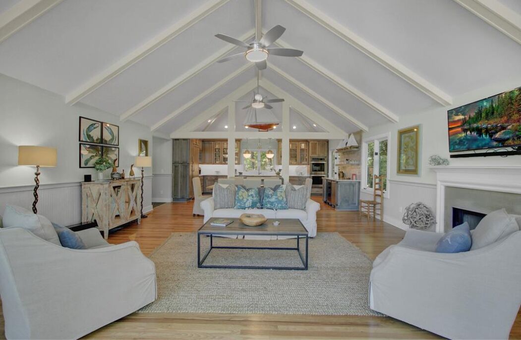 A spacious living room with a high ceiling, a fireplace, and a large TV.