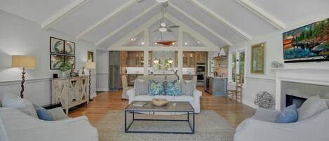 A spacious living room with a high ceiling, a fireplace, and a large TV.