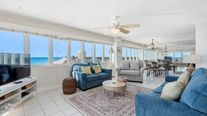 A spacious living room with a large TV, two sofas, a dining area, and a view of the beach. - D1001 Direct Gulf-Front View, 3 Pools, Tennis (Panama City Beach)