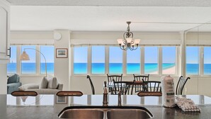 A dining area with a view of the ocean, a chandelier, and a table with chairs. - D1001 Direct Gulf-Front View, 3 Pools, Tennis (Panama City Beach)