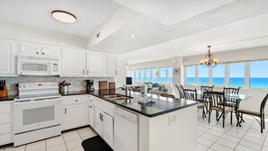 A modern kitchen with white cabinetry, a central island, and a view of the ocean. - D1001 Direct Gulf-Front View, 3 Pools, Tennis (Panama City Beach)
