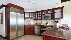 Una cocina moderna con electrodomésticos de acero inoxidable, armarios de madera y encimera de granito.