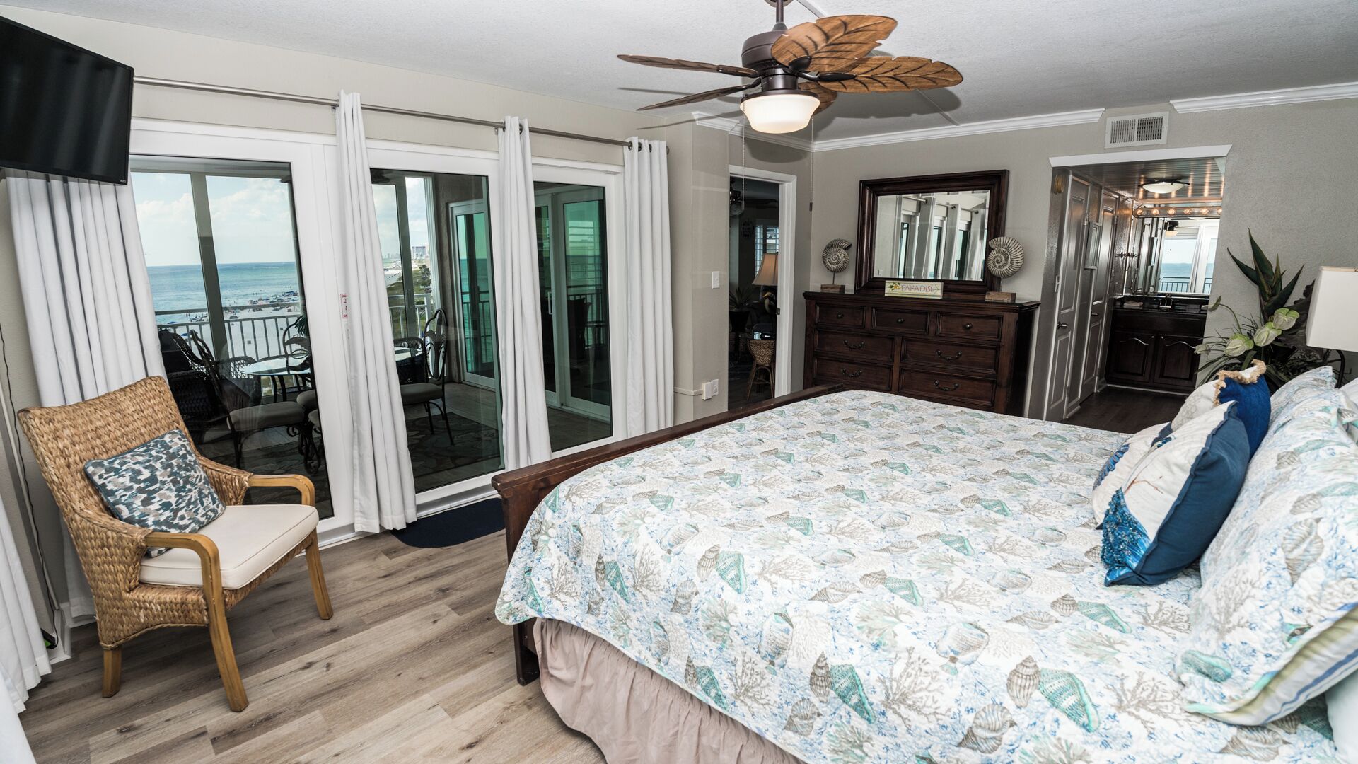 Une chambre à coucher avec un grand lit, une chaise, une commode et un ventilateur de plafond.