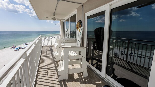 A balcony with white chairs and tables, overlooking a beach with umbrellas and people. - D601 Direct Gulf View, 3 pools, Tennis Court (Panama City)