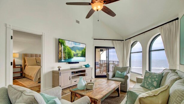 A spacious living room with a large flat-screen TV, comfortable seating, a wooden coffee table, and a ceiling fan. - 513 Seascape by AvantStay Oceanfront Home w/ Amazing View & Community Pool (Isle of Palms)