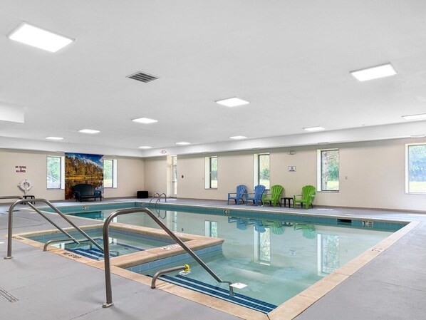 Una piscina interior con superficie de agua cristalina, rodeada por un solado de baldosas.