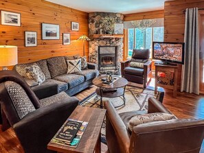 A cozy living room with a stone fireplace, leather furniture, and a television.