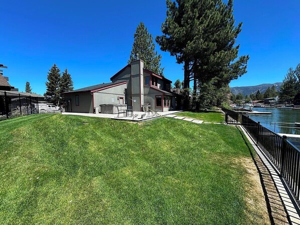 A house with a large lawn and a dock by a body of water.