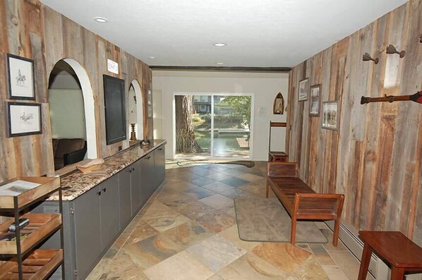 Un pasillo con pared de madera, una zona de cocina con mostrador y vistas al exterior.
