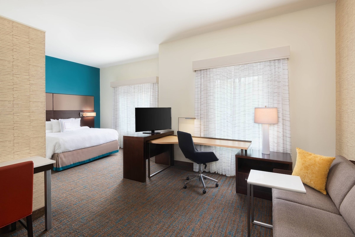 A hotel room with a bed, desk, chair, and a sofa.