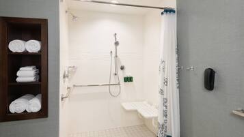 A shower area with a grab bar, a shelf with towels, and a toilet.