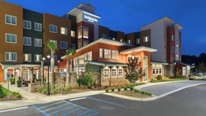 A multi-story hotel with a modern design, featuring a mix of brick and stucco exteriors, and a well-lit entrance area with outdoor seating. - Residence Inn by Marriott Spartanburg Westgate (Spartanburg)