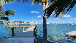 A wooden dock leading to a marina with boats and a clear blue sky. - Hope Town harbor period home with lighthouse view (Hope Town)