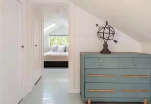 Un pasillo con un aparador azul claro, un globo decorativo y una cama al fondo.