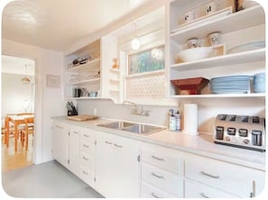 Una cocina moderna con armarios blancos, un fregadero y una encimera con diversos utensilios de cocina.