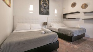 Habitación de hotel con dos camas, un cuadro y un estante en la pared con sombreros.
