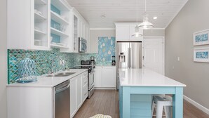 A modern kitchen with white cabinets, a blue island, and a patterned backsplash. - Amazing View from this Contemporary, Upscale Condo, Parking, Pool - Baywatch E10 (Pensacola Beach)