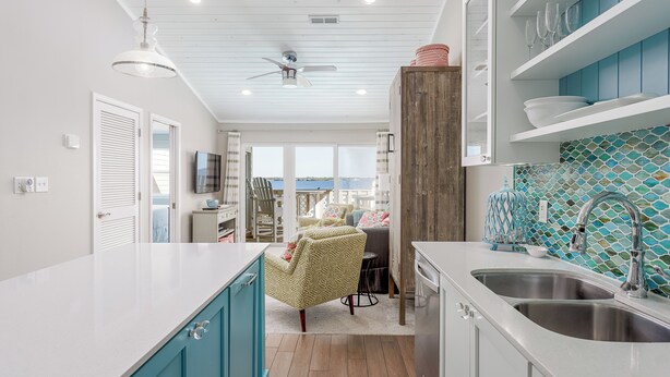 A modern kitchen with a large island, a dining area with chairs, and a view of the sea. - Amazing View from this Contemporary, Upscale Condo, Parking, Pool - Baywatch E10 (Pensacola Beach)