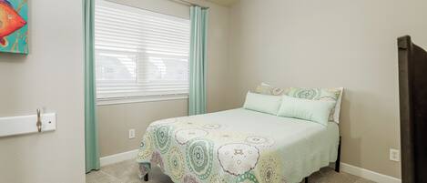 Un dormitorio con una cama, una ventana con cortinas, un cuadro en la pared y suelo alfombrado.