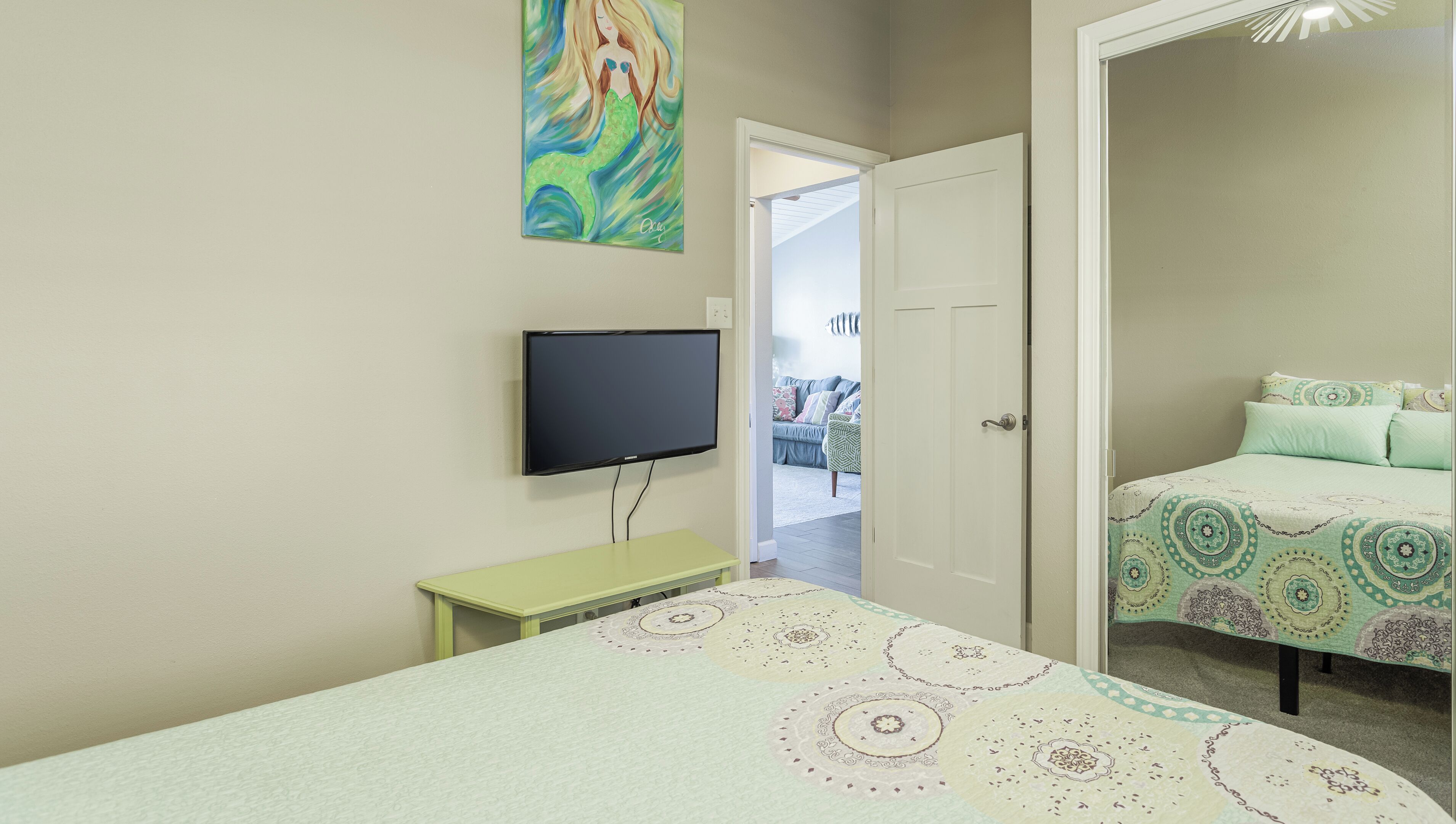 Une chambre à coucher avec un lit, une télévision, une porte et un tableau au mur.