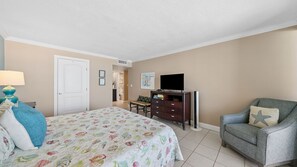 A hotel room with a bed, a desk, a chair, a television, and a wall-mounted air conditioning unit. - E804 Balcony overlooks the beach! 3 Pools (Panama City)