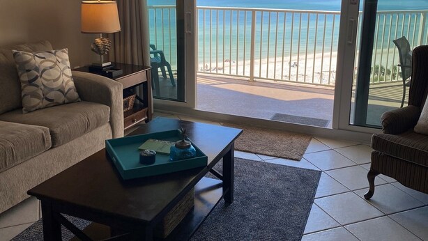 A hotel room with a balcony overlooking a beach.