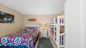 A bedroom with a bed, bunk beds, a nightstand, a lamp, and wall art. - E804 Balcony overlooks the beach! 3 Pools (Panama City)