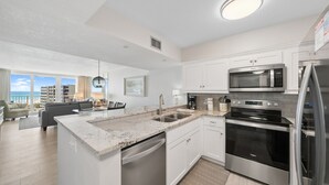 A modern kitchen with white cabinetry, a built-in microwave, and a stainless steel refrigerator. - C602 Sunset View, 3 Pools, Gulf Front (Panama City)