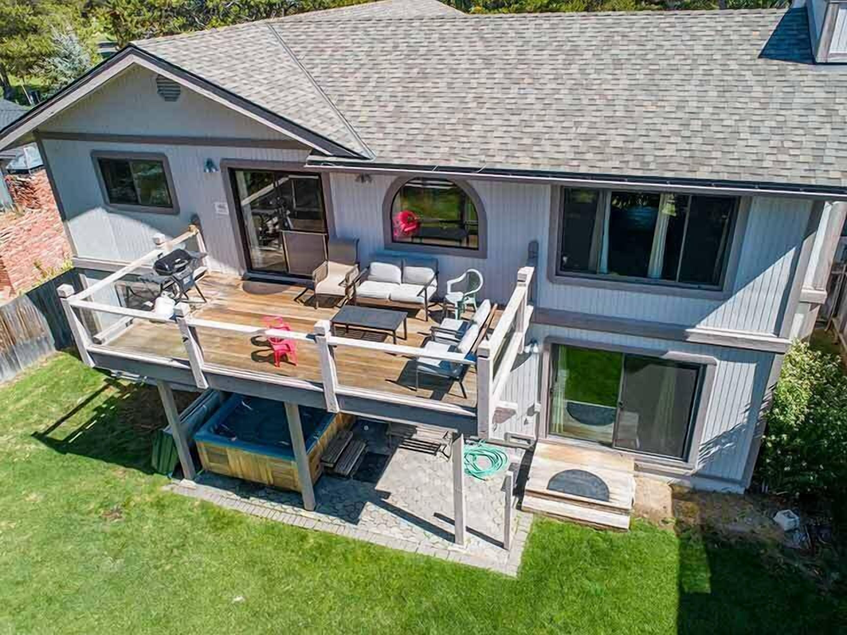 A two-story house with a covered deck, outdoor seating area, and a large sliding glass door.