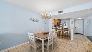 Un comedor con una mesa y sillas de madera, un candelabro y una cocina al fondo.
