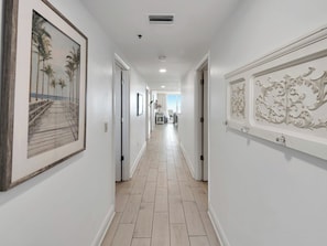 A hallway with framed artwork, a wooden floor, and white walls.