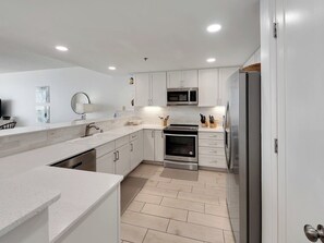 A modern kitchen with white cabinetry, a stainless steel refrigerator, a microwave, and an oven.
