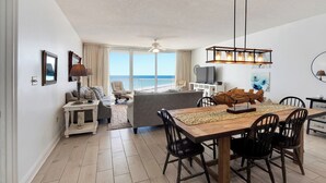 A spacious living area with a dining table, chairs, a sofa, and a TV.