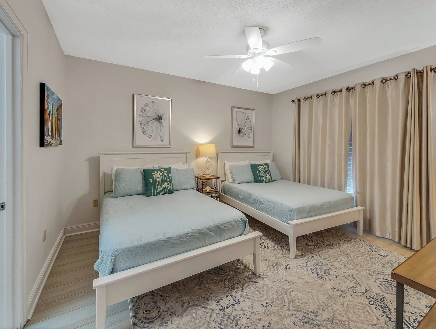 Een slaapkamer met twee bedden, een plafondventilator en een kamerkleed met dessin.